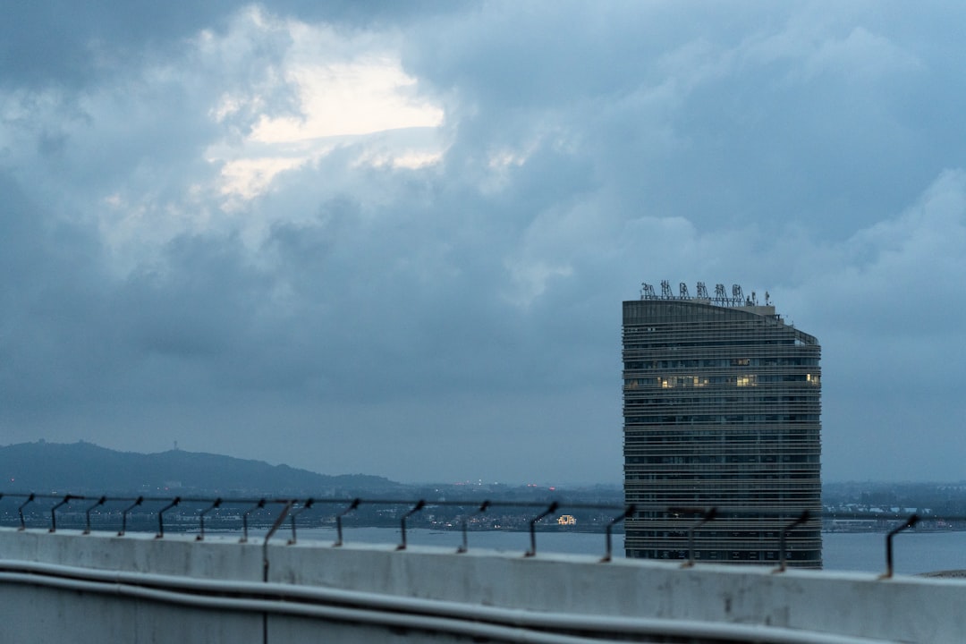 Tall building on the waterfront under cloudy sky